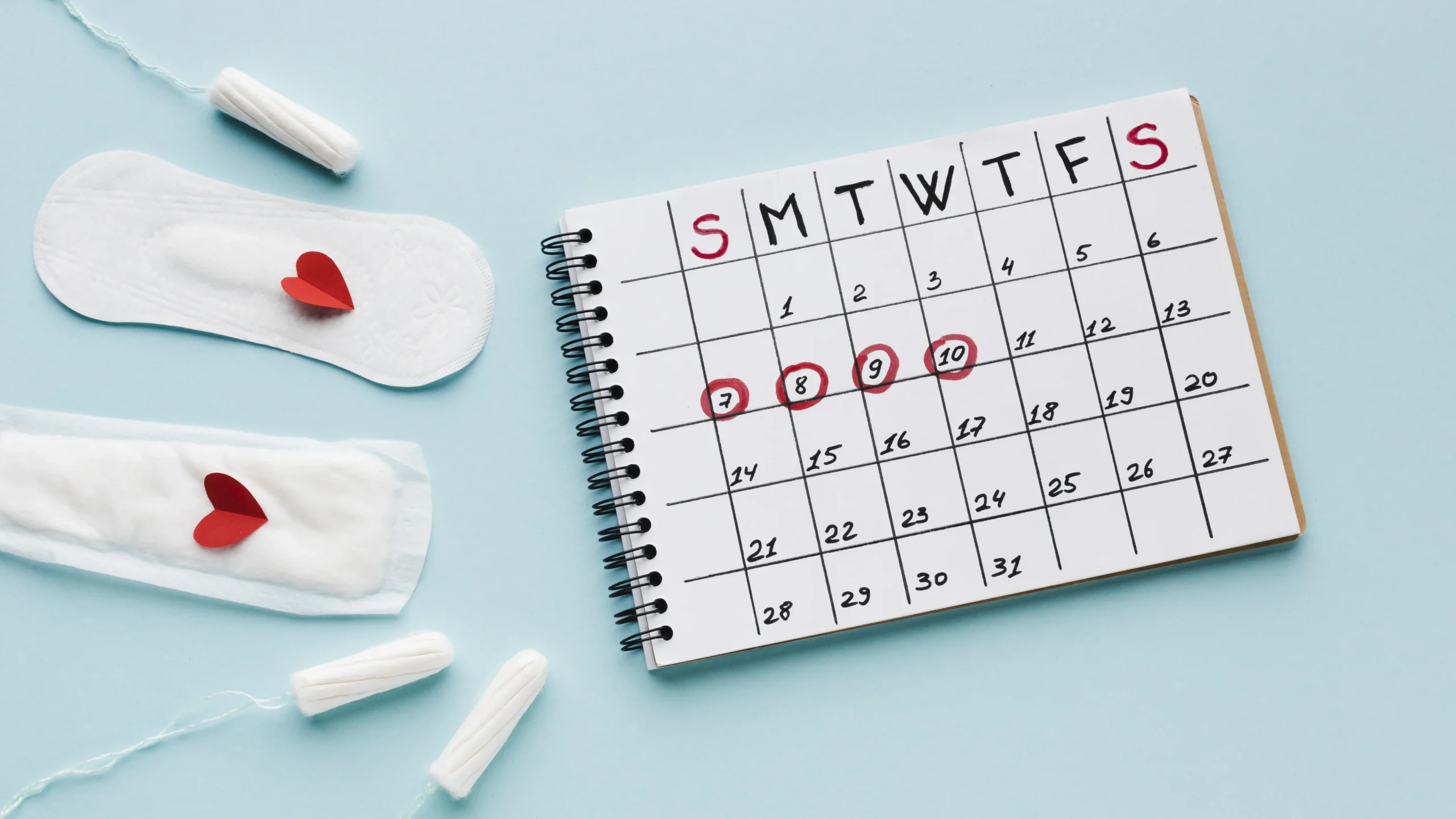A calendar marked with period dates, accompanied by menstrual pads and tampons, illustrating the topic of menstruation and addressing Why Is My Period Blood Brown