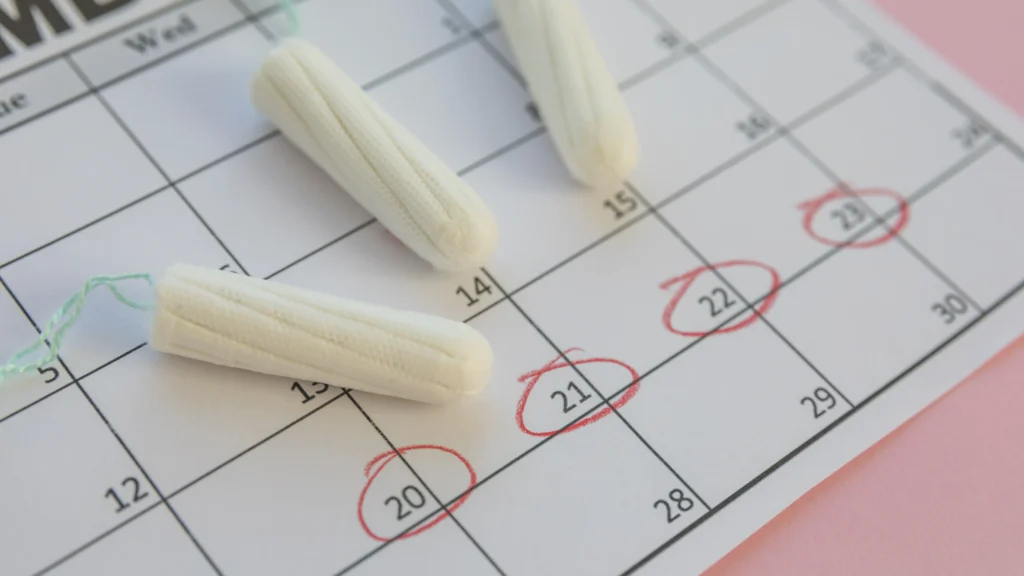 A calendar with marked dates and tampons, illustrating the connection between hormonal fluctuations during menstruation and what causes acne