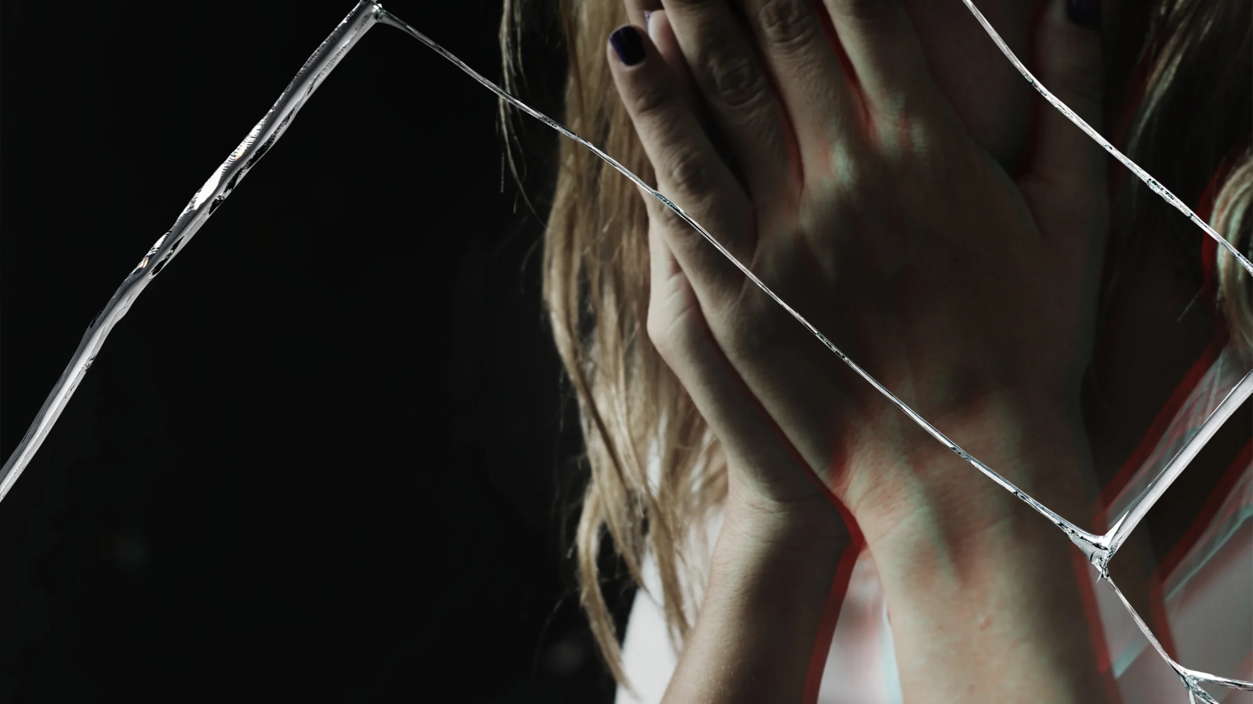 A girl gripping a metal fence, illustrating the physical manifestation of mental stress and how mental health affects physical health.