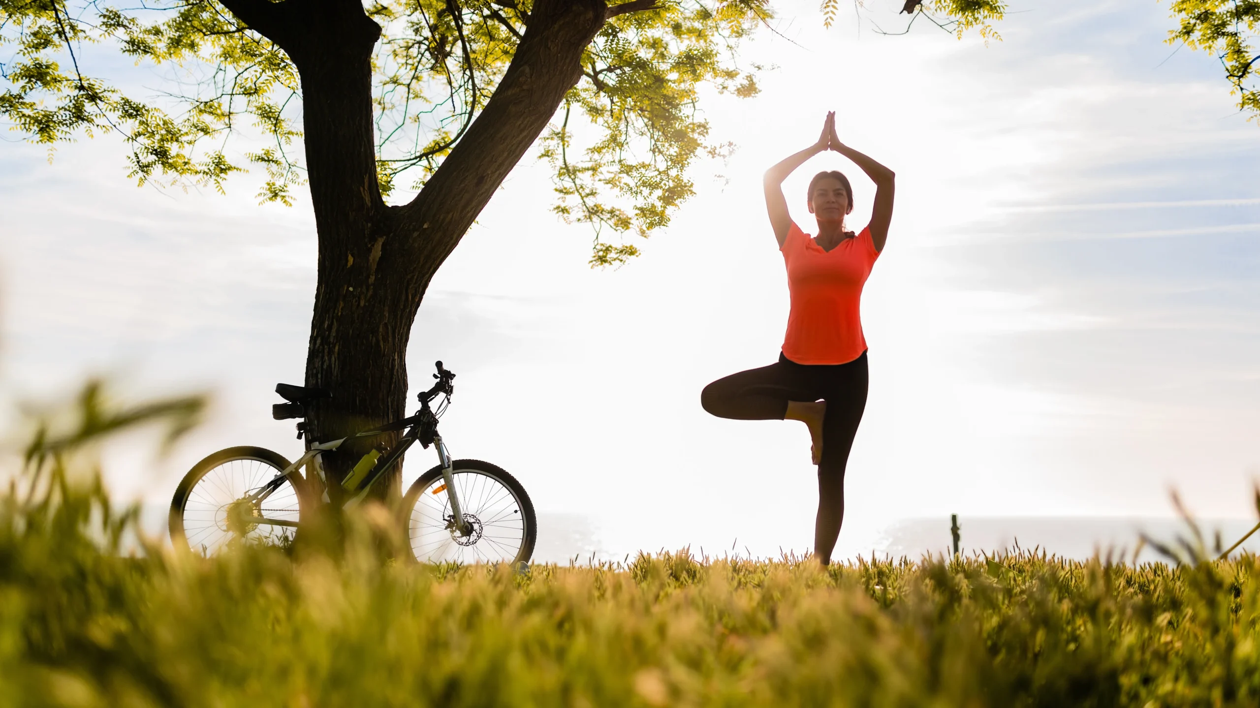 Woman practicing yoga in a park, demonstrating how mental health practices like mindfulness can improve physical well-being.