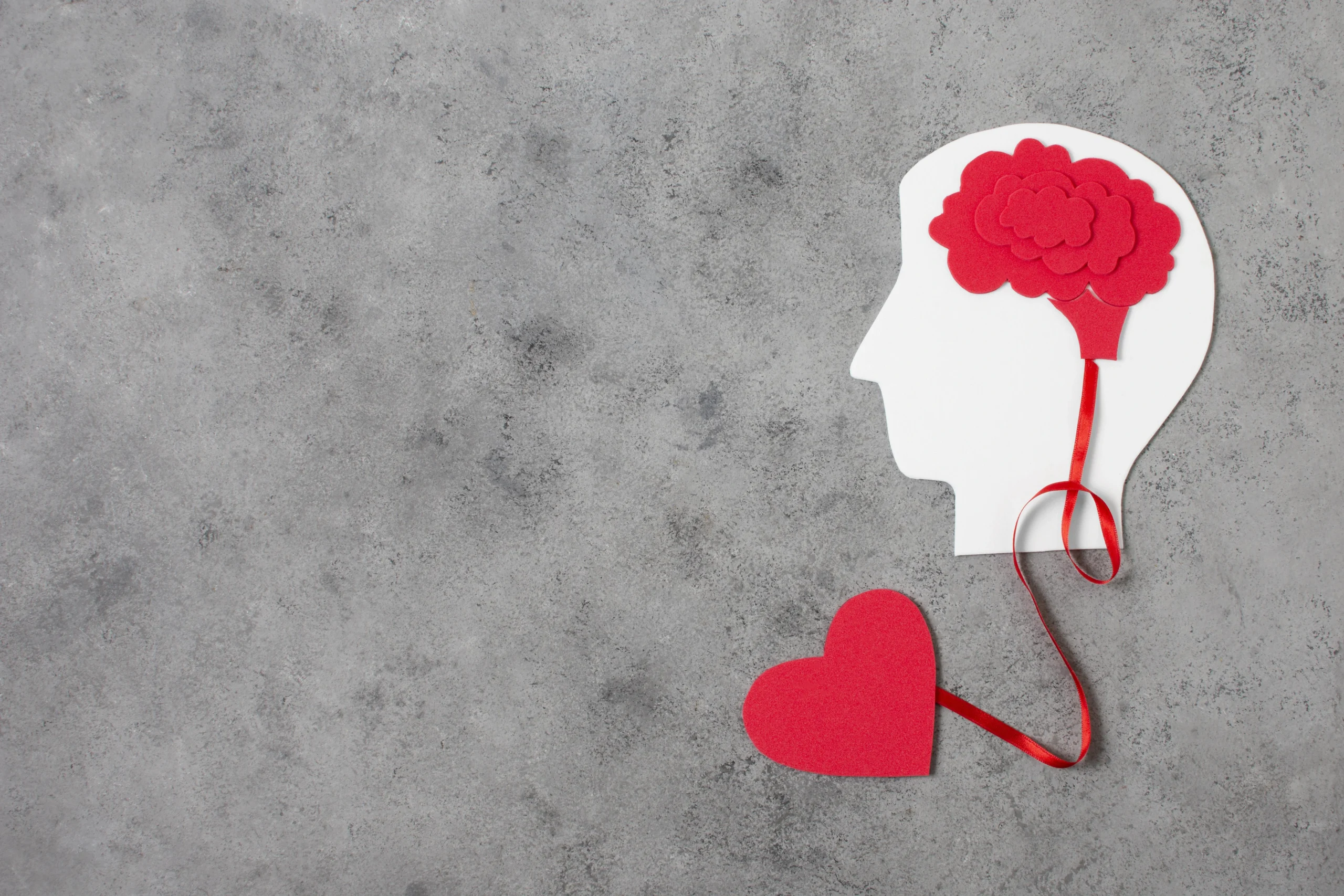 Human head silhouette with a floating brain connected to a heart by a ribbon, symbolizing the connection between mental health and physical well-beingand How Mental Health Affects Physical Health.
