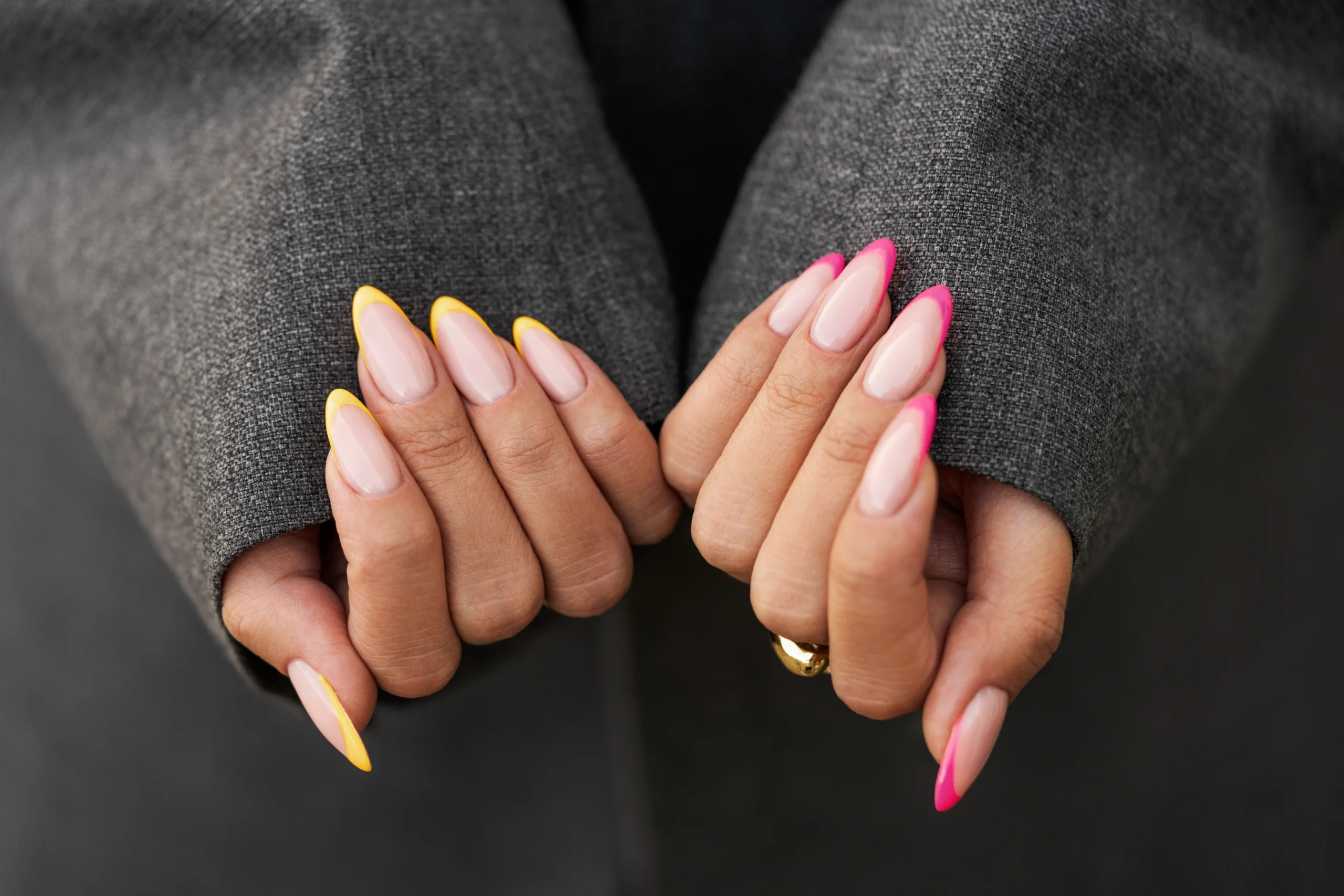 A close-up of a hand with long, glossy acrylic nails in pink and yellow, showcasing how long acrylic nails last with proper care.
